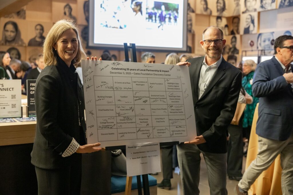 Amy Carter and CEO Mark Suzman hold up a poster with the 25 local grantees honored for the Gates Foundation’s 25th anniversary.