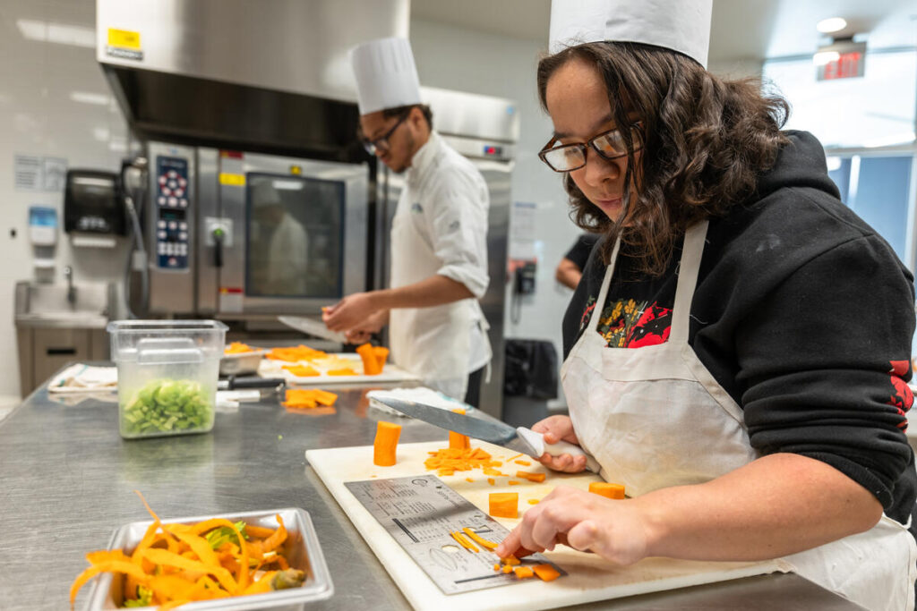 Culinary students chopping carrots.