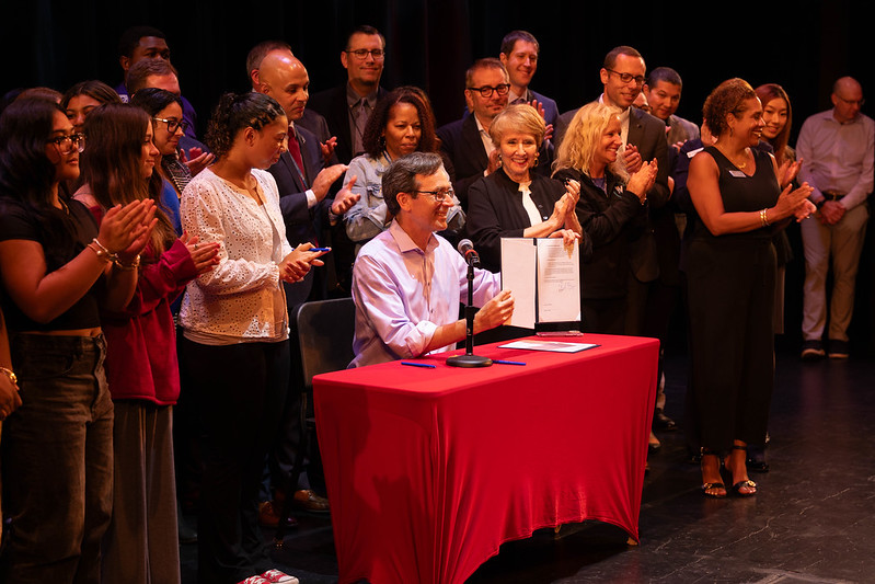 Governor Bob Ferguson holds up an executive order at an event announcing the Washington Completes FAFSA campaign.