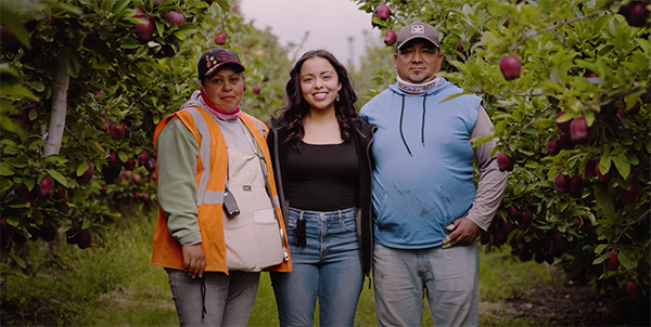 Maria Cisneros standing with her parents together.