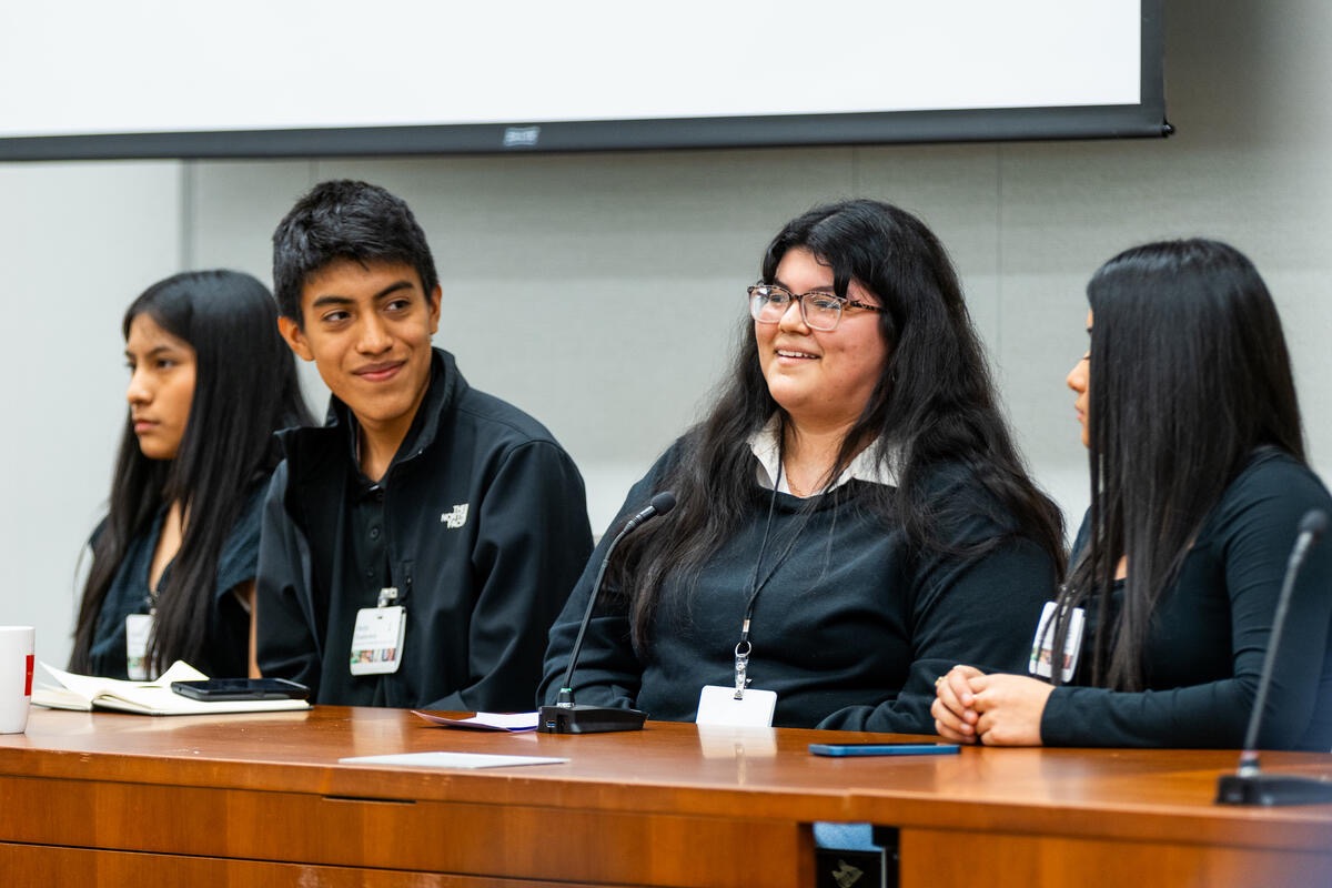 Four students smile and talk to each other.